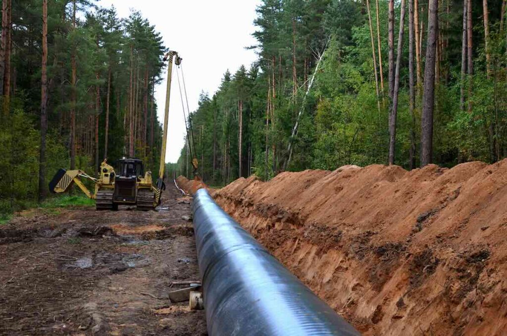 Pipeline installation site in a forest with heavy machinery and exposed soil, illustrating land disruption ideal for hydroseeding for oil and gas.